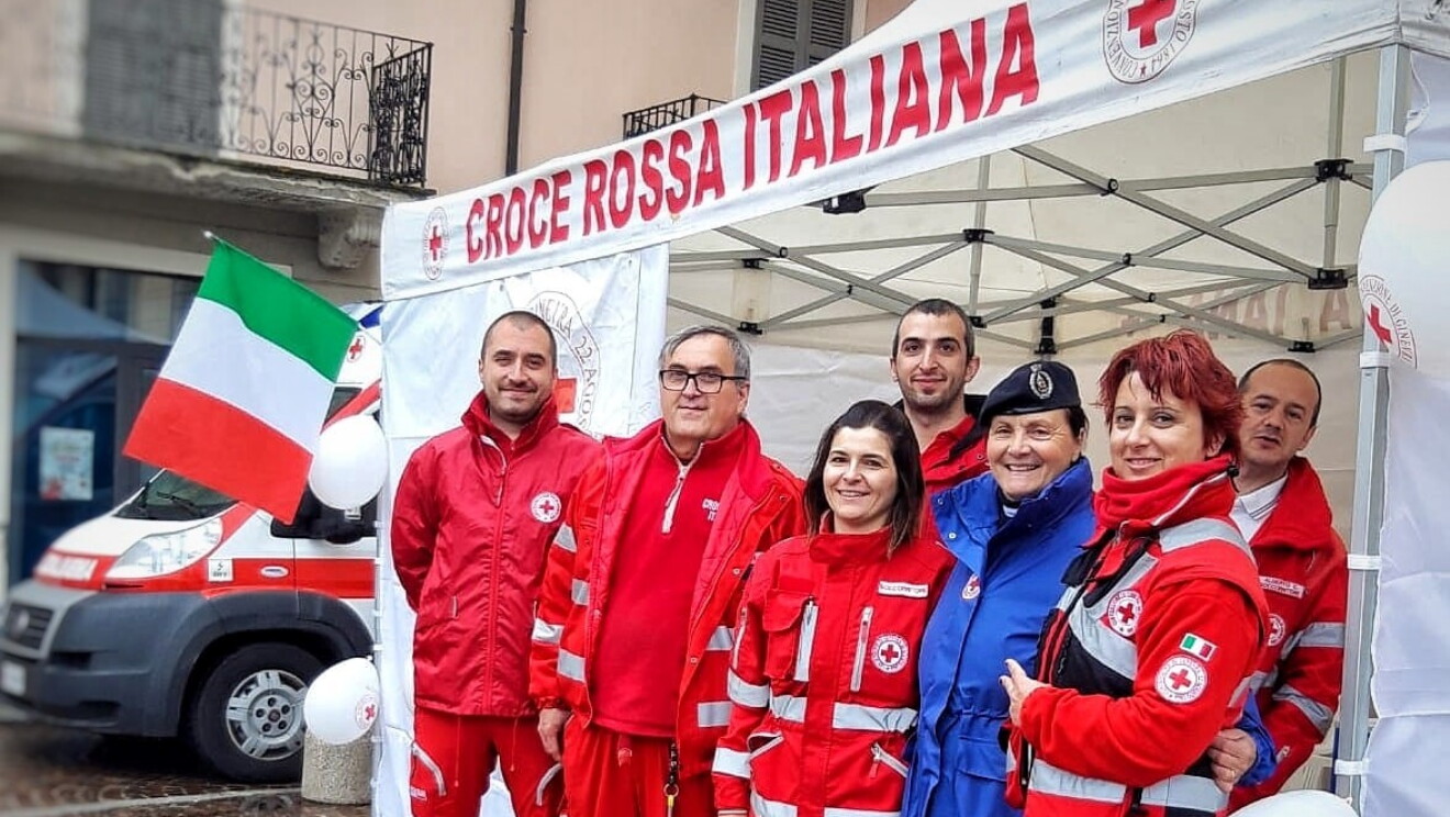 Volontari della Croce Rossa in gruppo sotto uno stand all'aperto. 