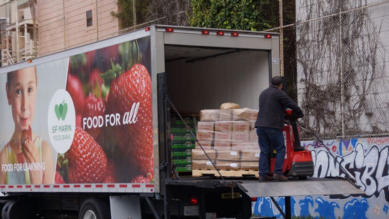 Food bank delivery truck unloading supplies in urban area