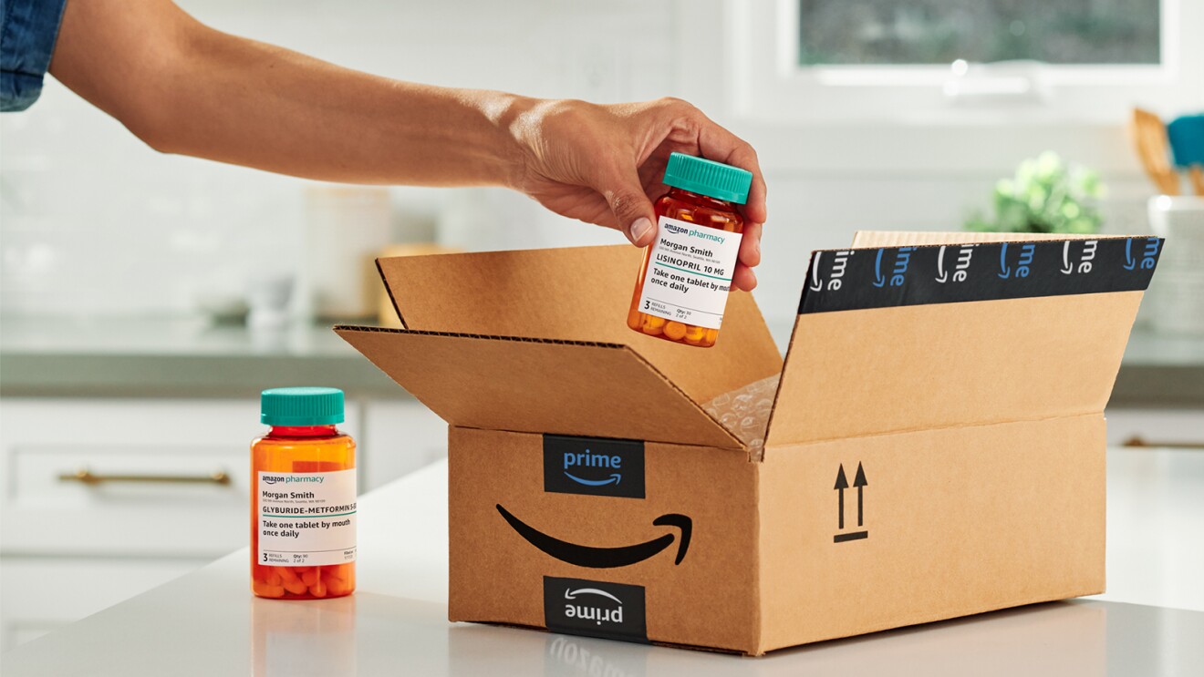 Image of hand pulling out a medication bottle from Amazon Pharmacy out of an open Amazon Prime cardboard box sitting on top of a kitchen countertop