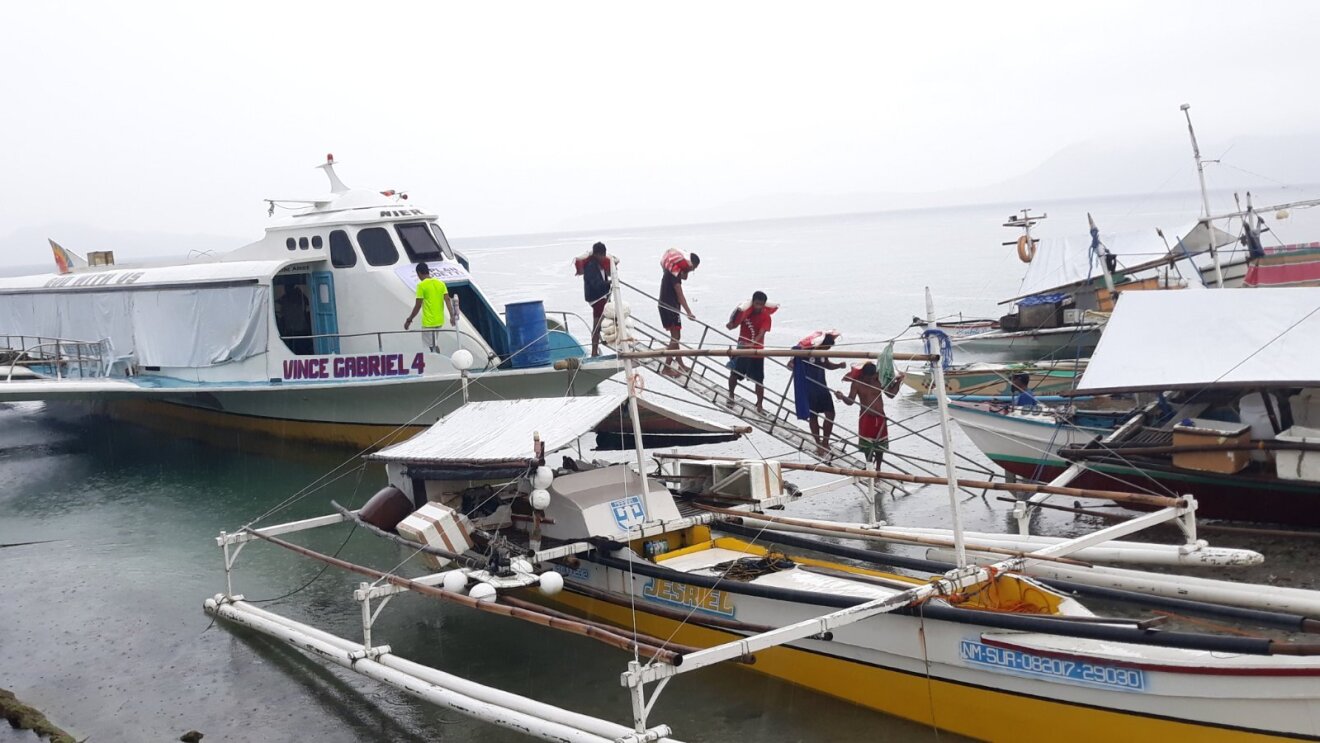 五个人携带食物袋可以看到下车Dinagat岛上的一艘船,菲律宾。