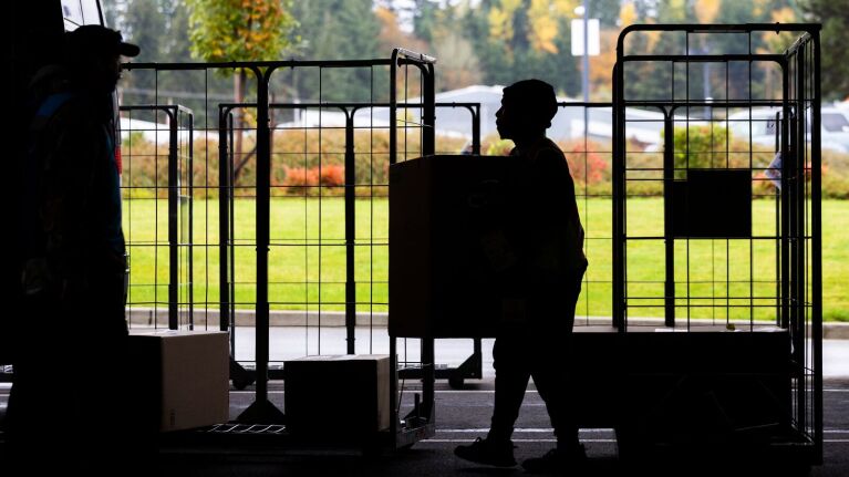 Silhouette of person carrying a package by delivery carts
