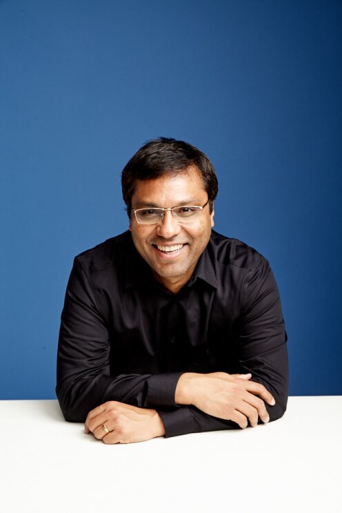 A portrait of Rohit Prasad, vice president and head scientist, Alexa AI. He is wearing a black shirt and is photographed against a blue background.