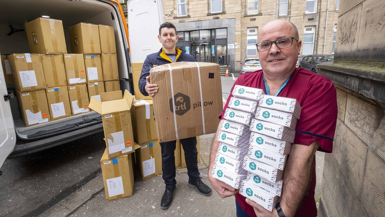 Two men hold some of the 5,000 compression socks they're donating to help Scottish nurses combat Covid-19