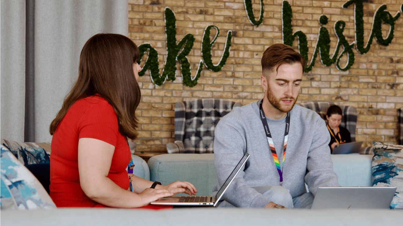Two colleagues working together on laptops in a modern office