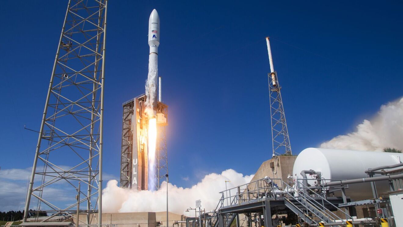 Space rocket igniting on launchpad against clear blue sky