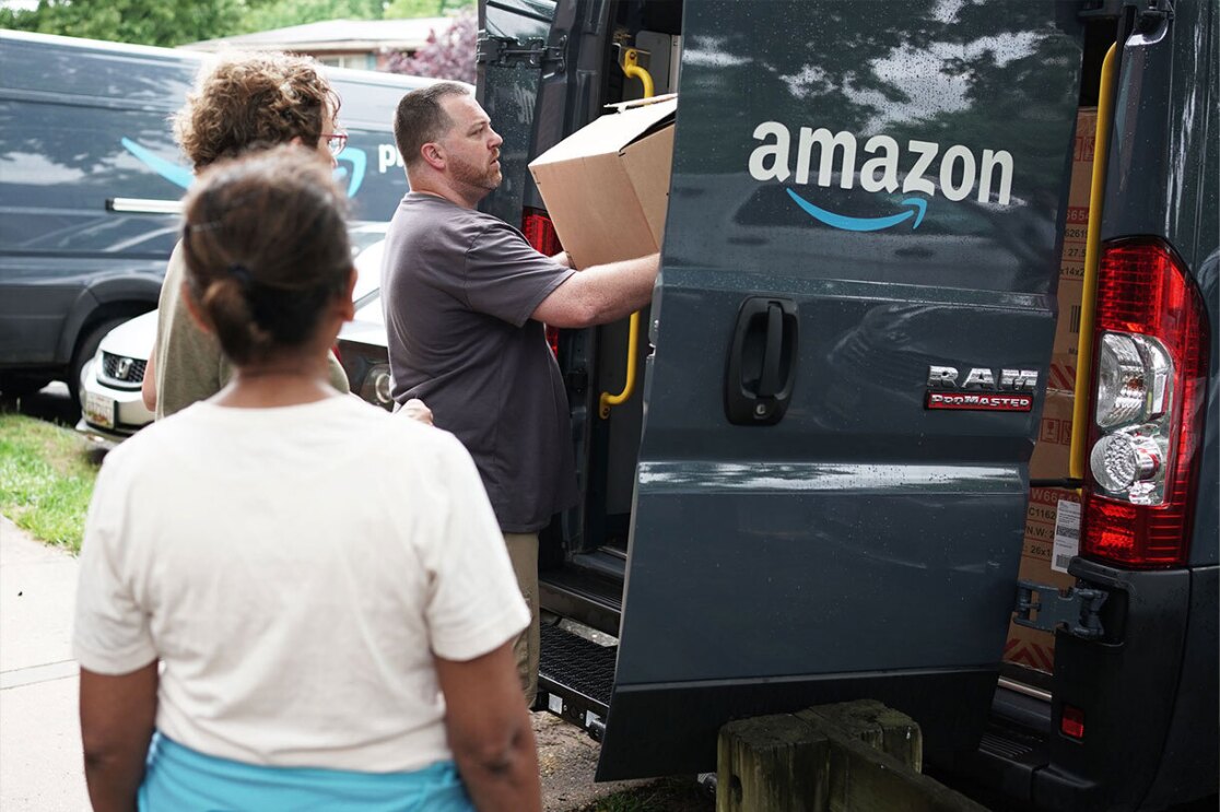 Volunteers and Amazon employees load up Amazon delivery vans with essential furniture and household products.