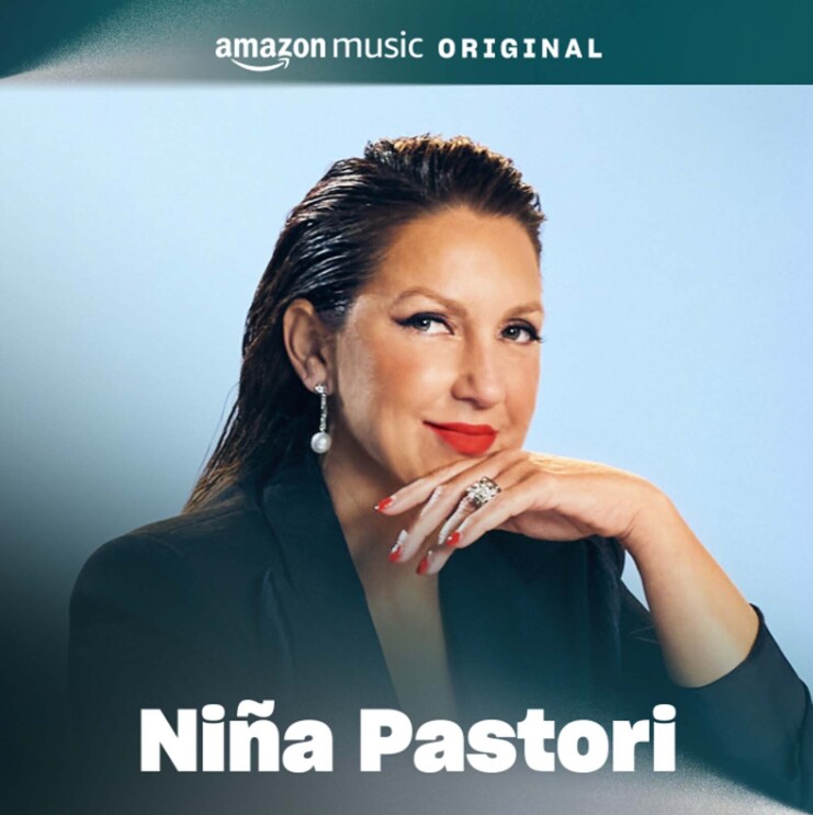 The cover art for Nina Pastori's song. It features a portrait of Nina smiling softly while looking at the camera. There is a blue background behind her and she is wearing bright-red lipstick.