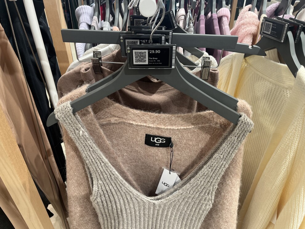 An image of a knit top on a rack with other clothing labeled with UGG brand tags.