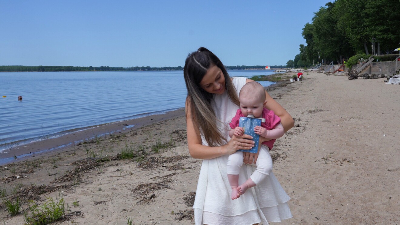 A woman holding her baby on a beach