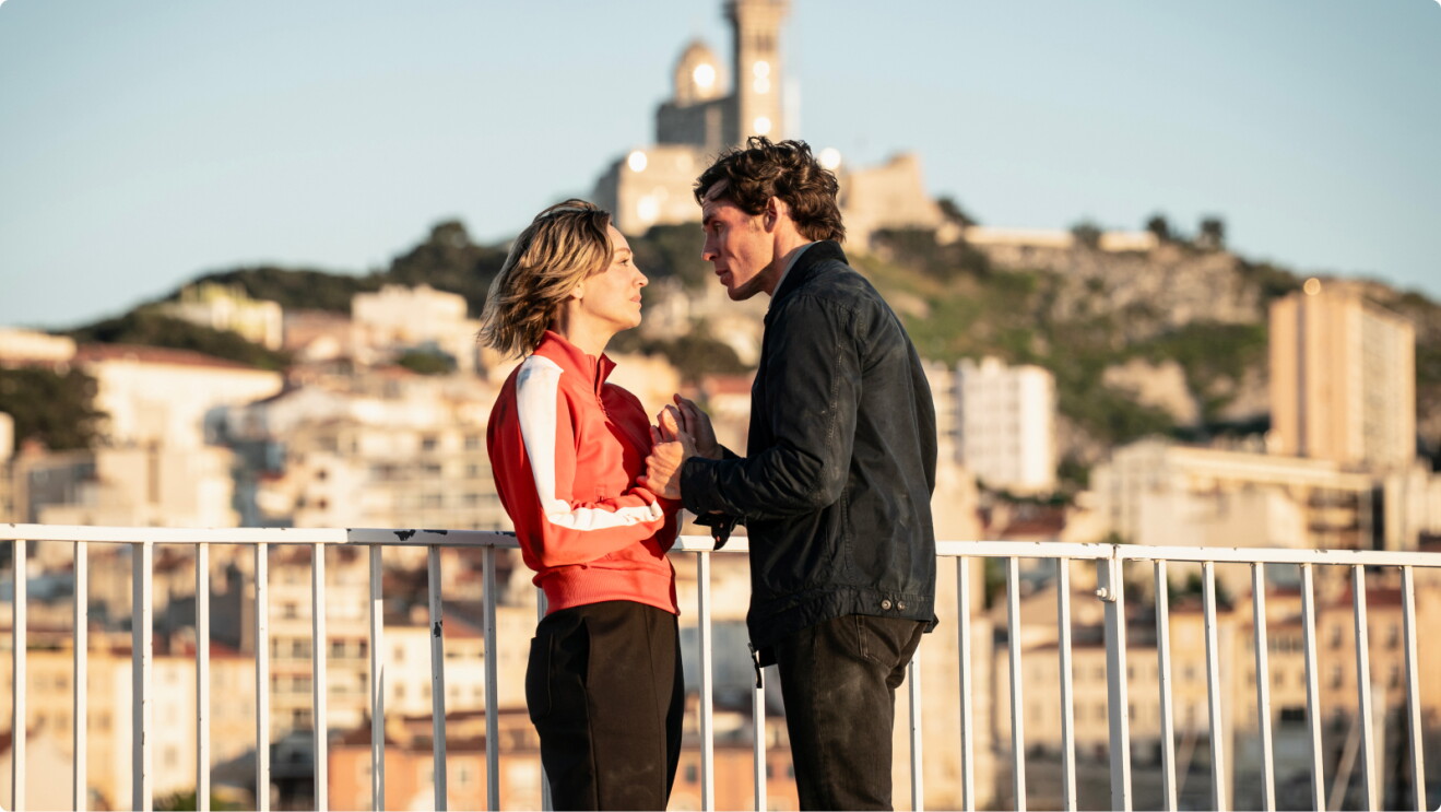 Vanished starring Kaley Cuoco and Sam Claflin on a balcony in the sun as the two hold hands.