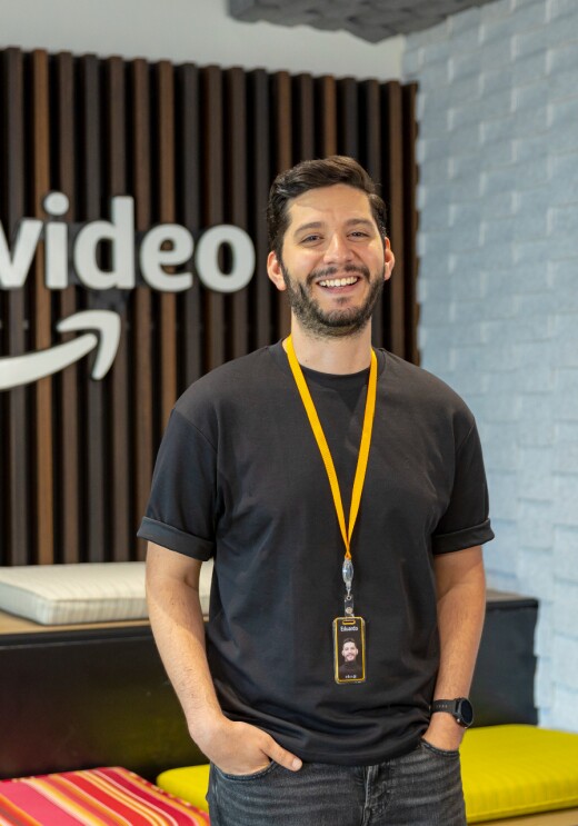 Foto de Eduardo Fiorenzano, especialista en Marketing Digital para Prime Video México. Está de pie con las manos en los bolsillos delante del logo de Prime Video.