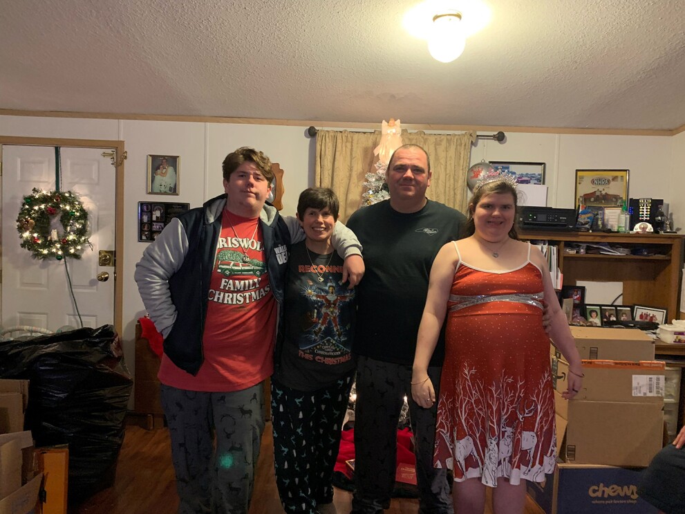 An image of a family standing and smiling for a photo in their home. 