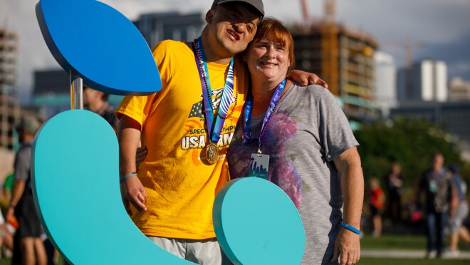 特殊奥林匹克运动会的运动员(男)拍照的女,美国游戏背后的标志。西雅图的一部分在后台天际线是可见的。