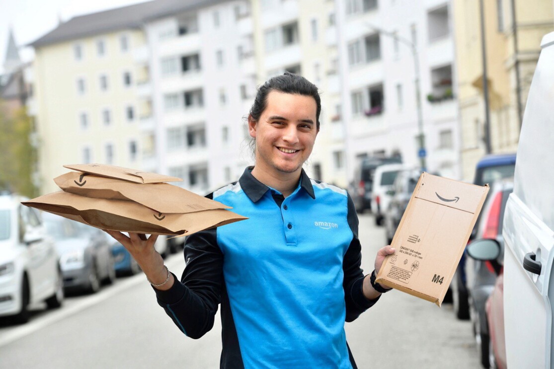 An Amazon Delivery Associate holding Amazon paper and cardboard packaging