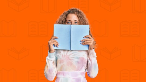 A woman holding a book infront of an orange background