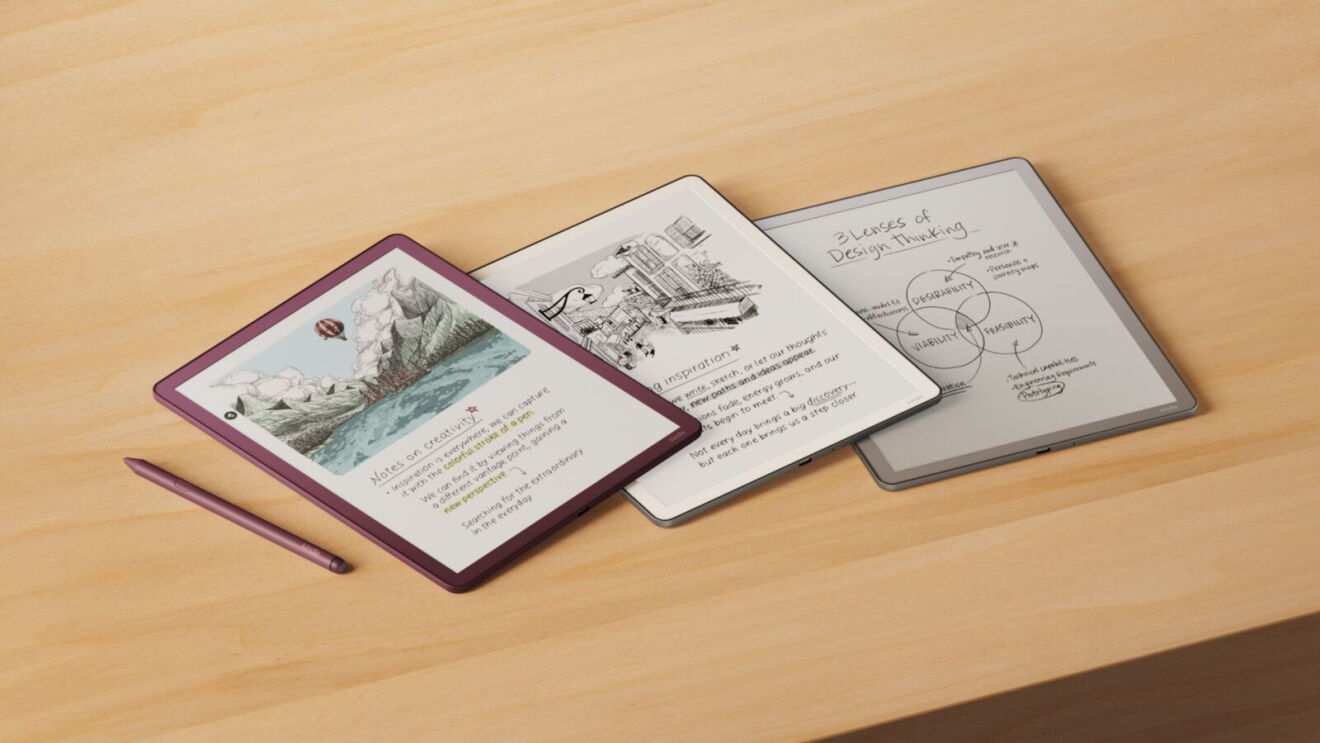 Three e-readers displaying different content - one with a colorful illustrated page, one with sketched notes, and one with a design thinking diagram - arranged on a wooden desk with a stylus