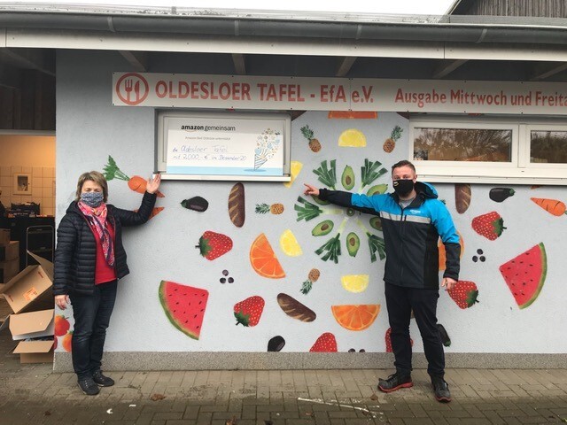 2 Personen mit Masken neben einem Spendenscheck