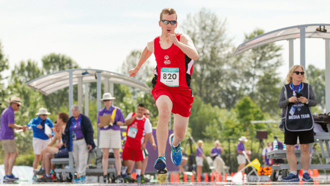 一个人的形象在比赛跑步。有些人站在背景。