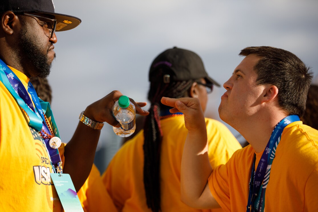 Two male closing ceremony attendees appear to jokingly "face off" as they face one-another.
