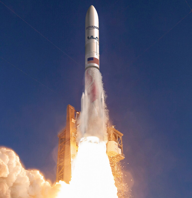 Ein Bild von einem Raketenstart. Auf der Rakete sind das Amazon-Logo und eine Flagge der Vereinigten Staaten zu sehen.