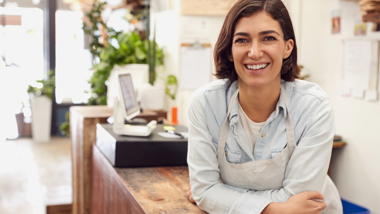 A woman working in a small business leans toward the camera.