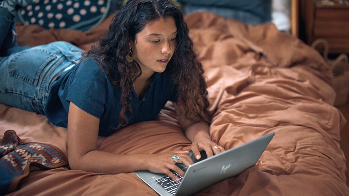 Prime Day 2023 live blog best deals: woman using her HP laptop while lying on her bed.