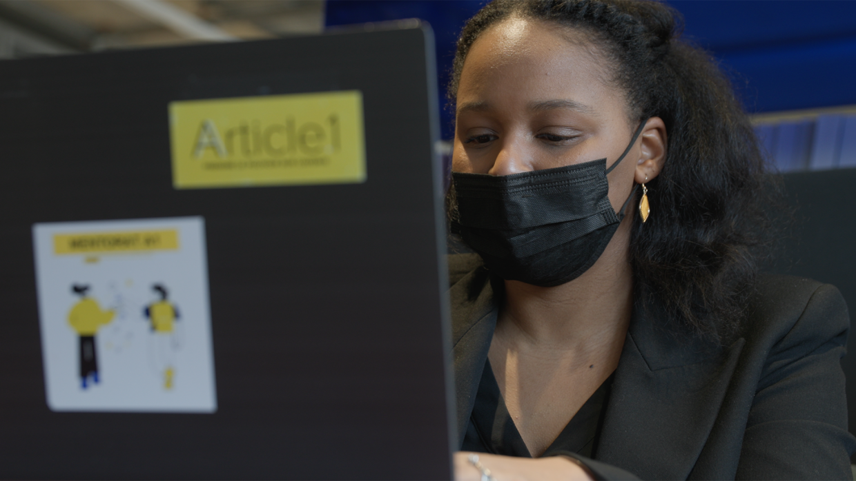 A woman wearing a mask and working on a laptop