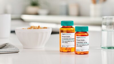 两个亚马逊药房药瓶坐在白色的厨房工作台面之间的一杯水和一碗麦片粥。