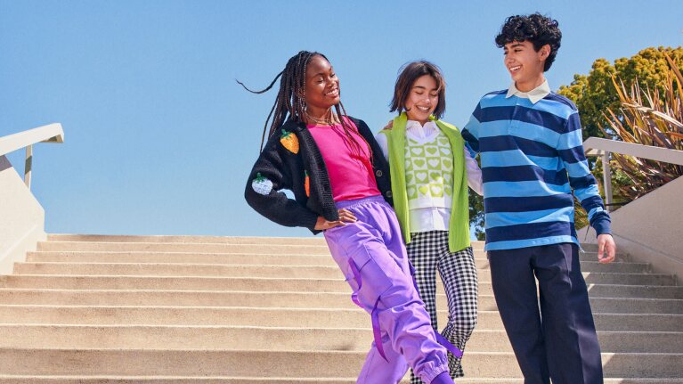 Children laughing  in colorful casual wear smiling on sunny outdoor steps