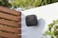Blink camera secured to a white wall surrounded by greenery