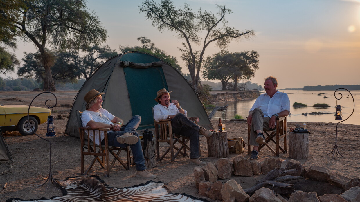 Three men sit around a campfire 