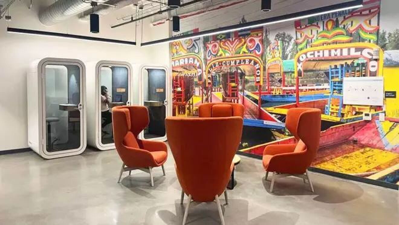 鮮やかな色の遊園地を描いた壁紙が貼られた部屋には、4脚の赤い椅子と3つの白い電話ブースが設置されている。