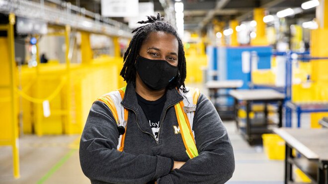 亚马逊员工站在实现中心用面具,看着相机。