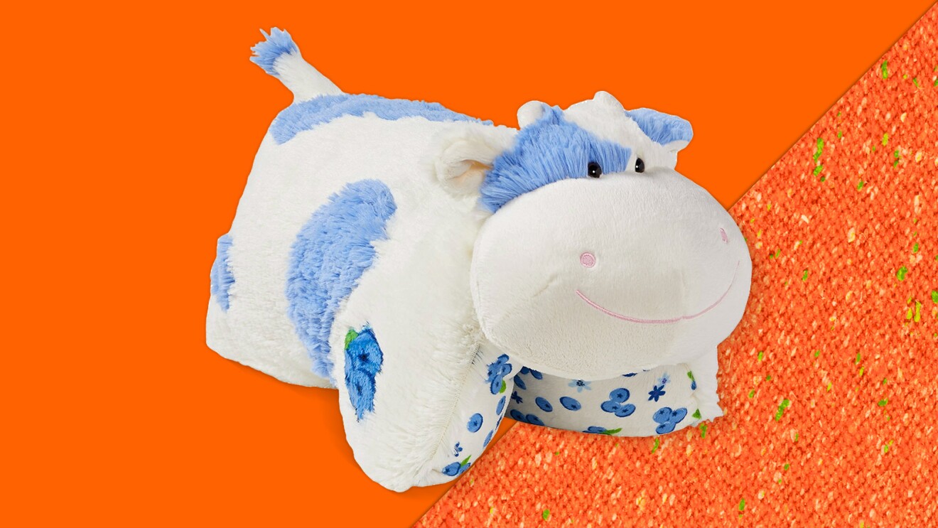 Plush cow toy with blue spots on orange background