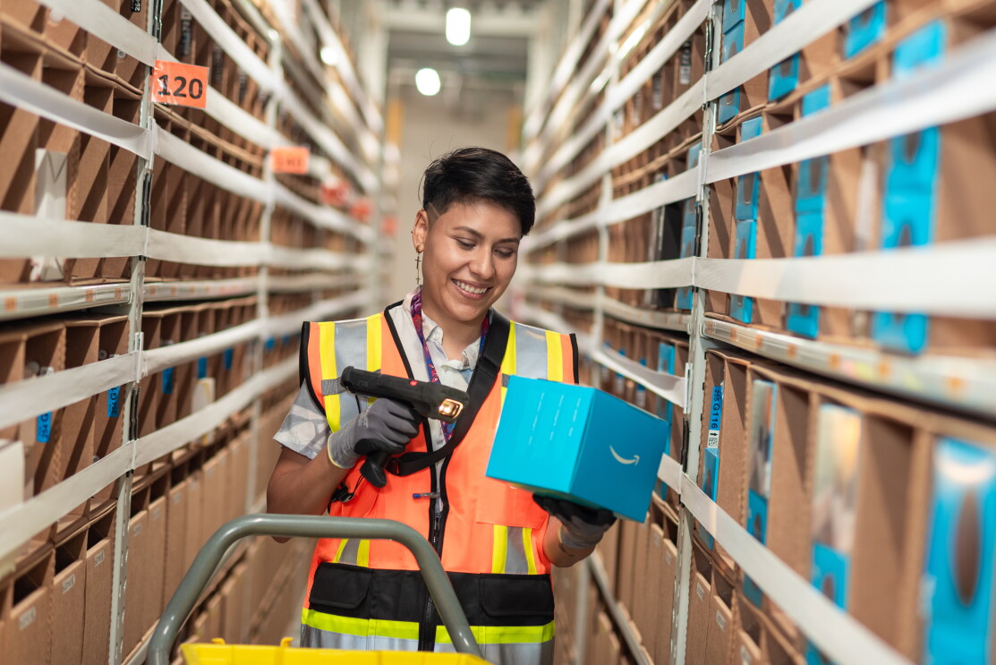 Trabajdora de un centro logístico de Amazon escaneando un producto. 