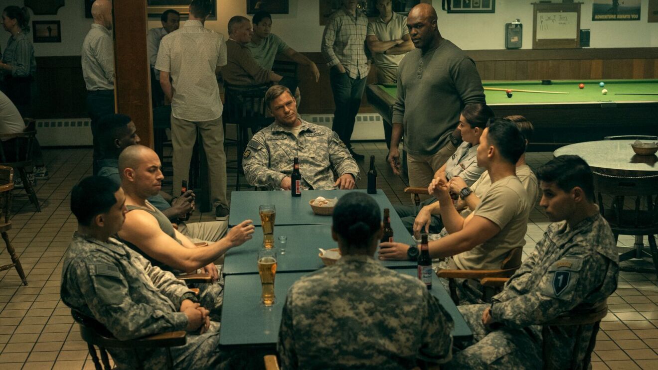 characters in the prime video series reacher dressed in military gear sitting around a table while drinking beers