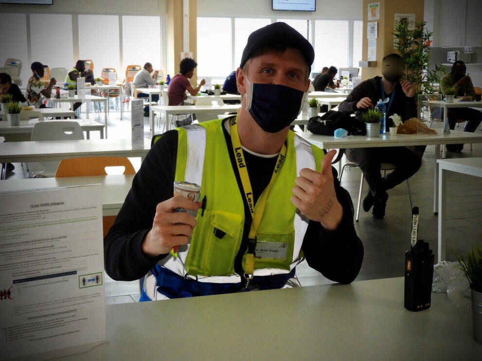 Ein Mitarbeiter mit Mundschutz und gelber Sicherheitsweste am Eisessen.