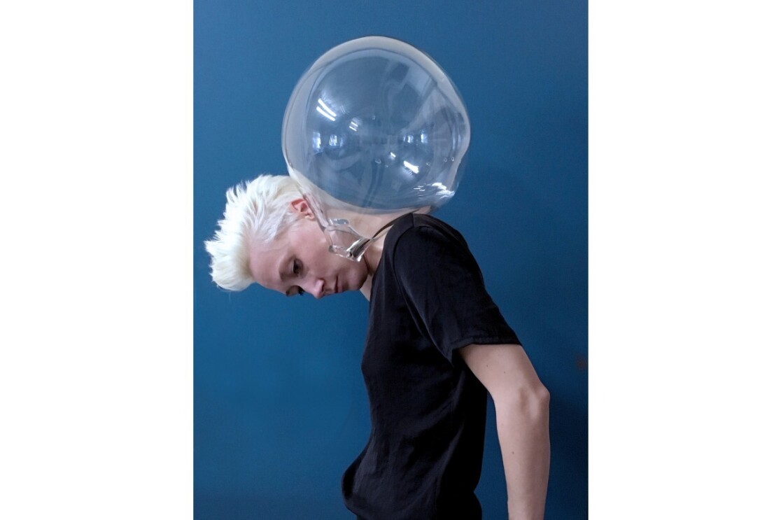 Anna Mlasowsky balances a glass bulb on her shoulders and looks down at the floor.