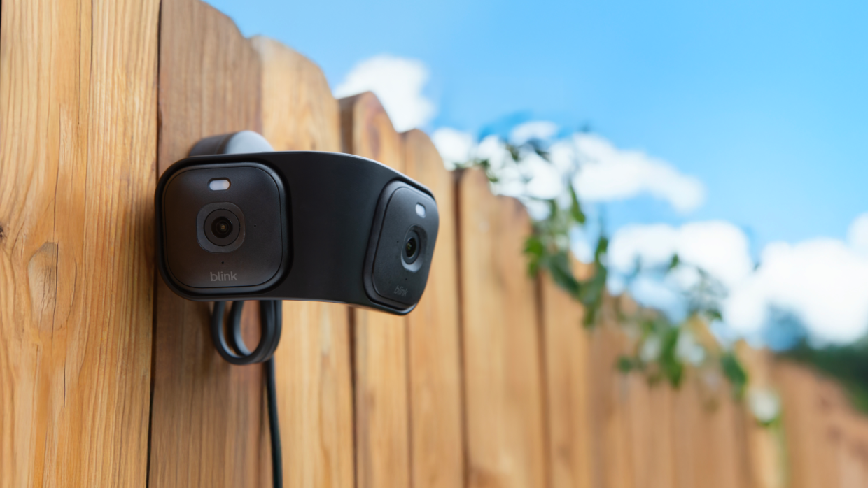Blink security camera mounted on wooden fence under blue sky
