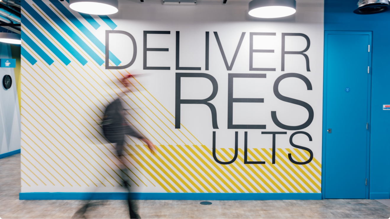 Artwork reading 'deliver results' on the wall of Amazon's London office