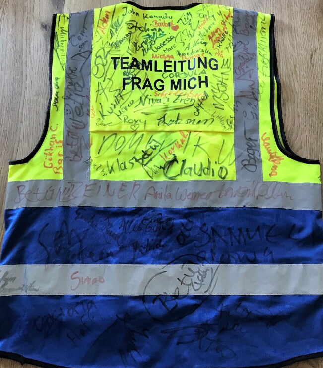 Mamadous Sicherheitsweste von hinten mit vielen Unterschriften von Kollegen.