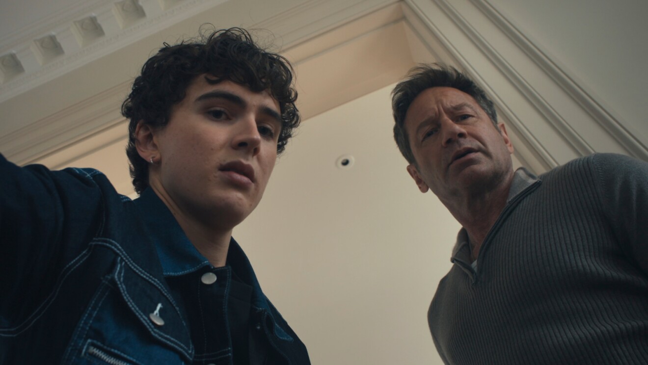 Two men looking down at camera, one young with curly hair, one older
