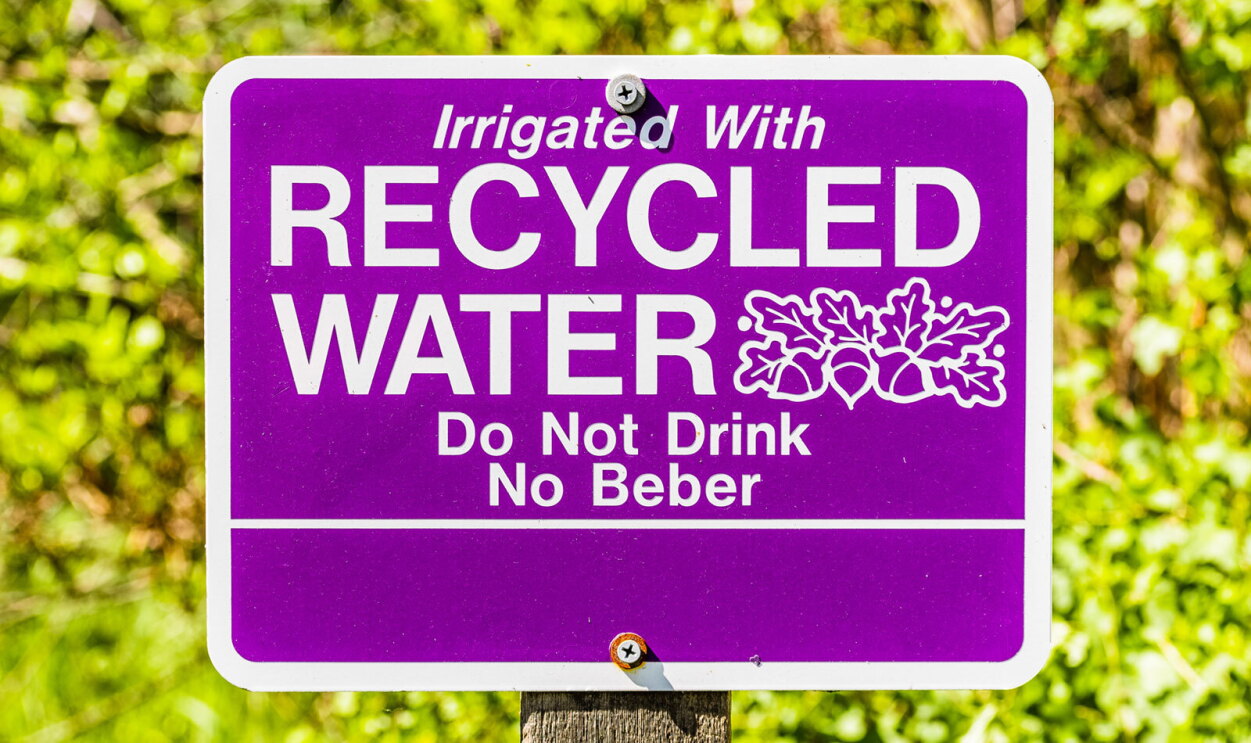 A photo of an outdoor sign that states, "Irrigated with recylcled water, Do Not Drink, No Beber".