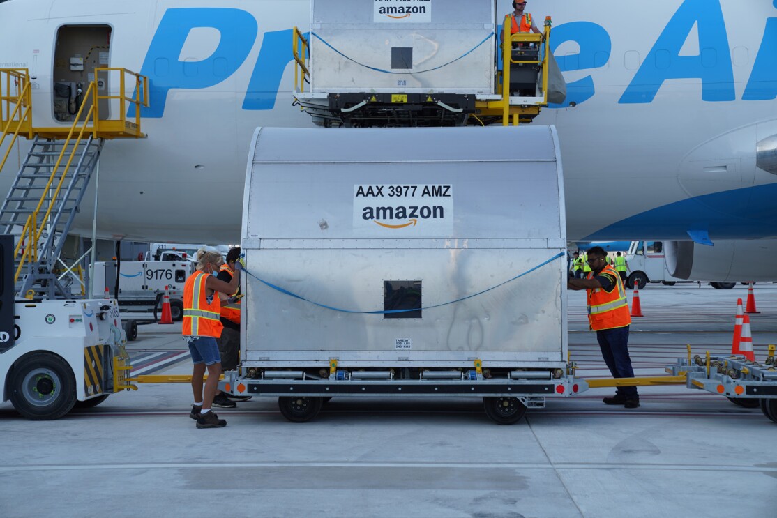 An image of a large metal container being loaded onto a Prime Air plane.