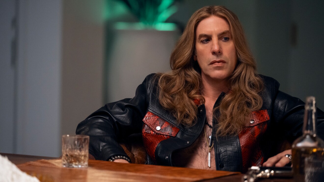 Sacha Baron Cohen with long blond hair and a leather Jacket in Balls Up