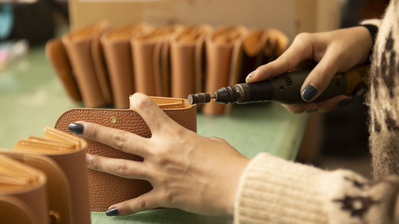 縫い終わった革の断面を工具でやすりがけする写真