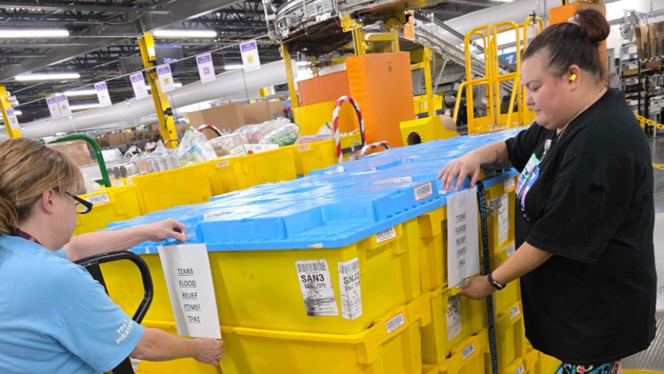Workers sorting packages in large yellow bins at distribution center