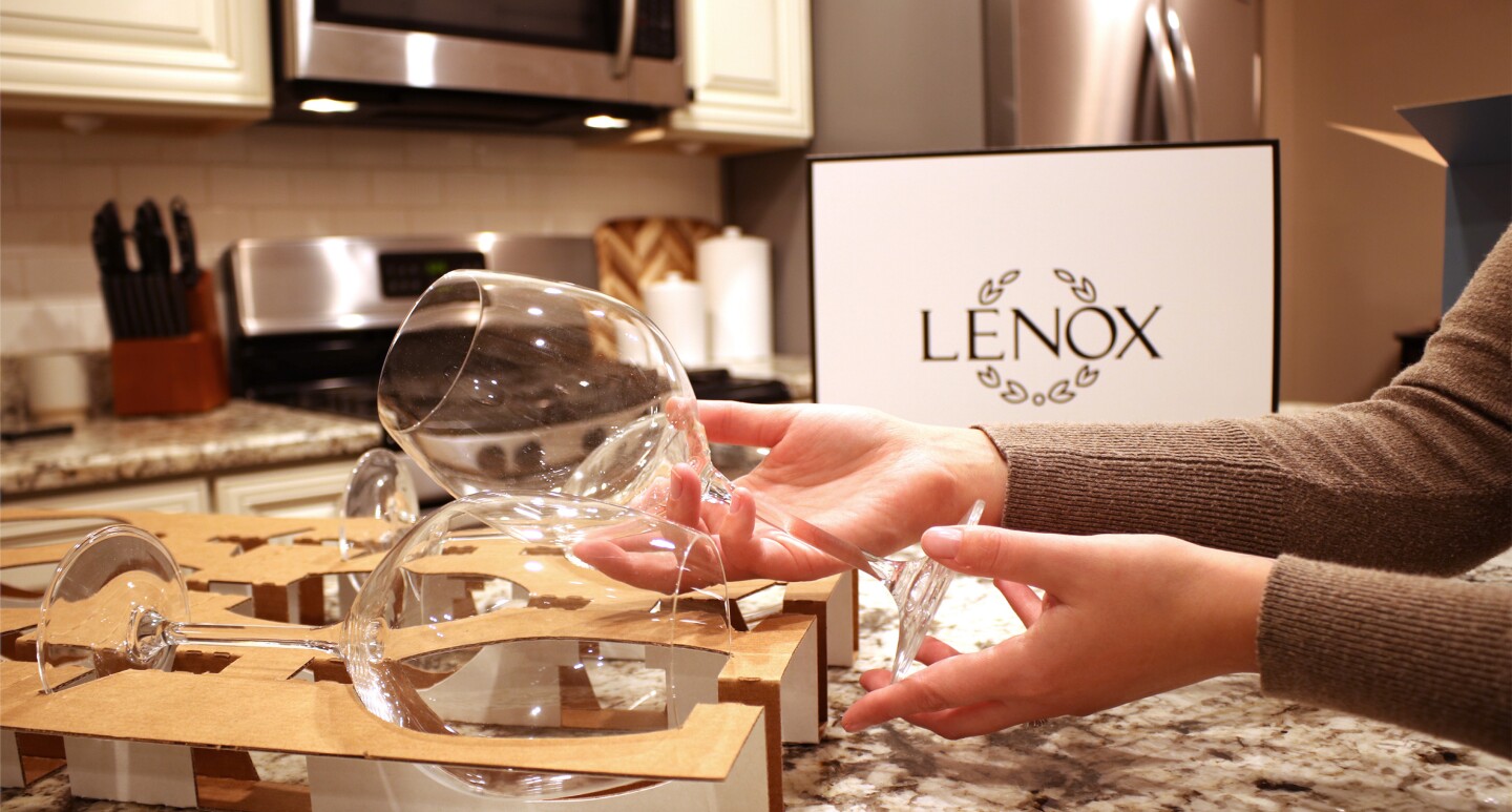 A person opens an improved Lenox wine glass package in their kitchen.