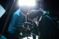 Two people intently examining professional camera equipment on set
