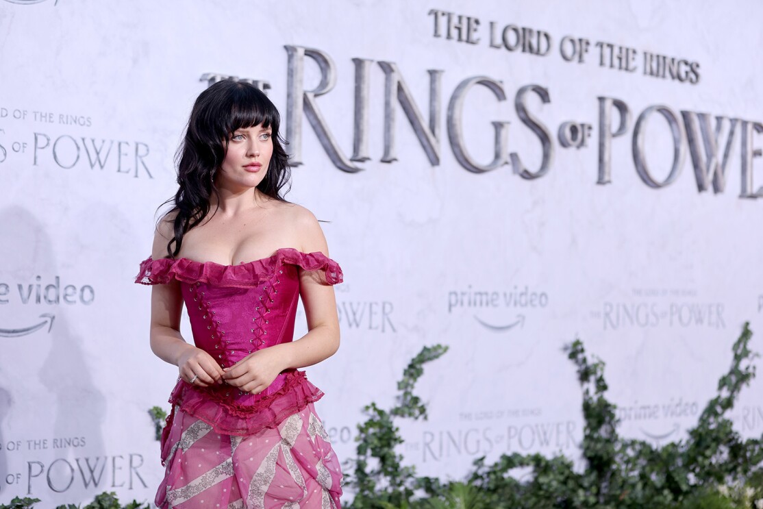 An actress stands for a photo in front of the Lord of the Rings the Rings of Power sign on the red carper